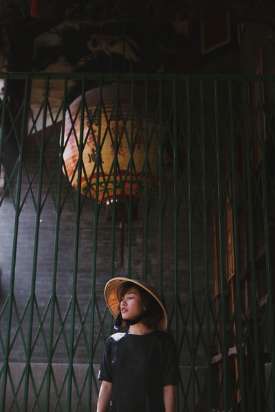 Wearing a brown bamboo hat woman standing near the metal door

